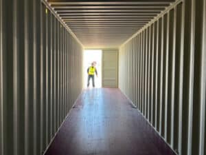 Interior of a used shipping container with one door open and a person at the end of the storage container, storage container rentals, used shipping containers for sale