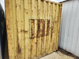 yellow 40 foot shipping container end with repair patch in metal